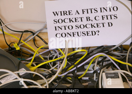Un groviglio di fili il computer sotto una scrivania in un luogo di lavoro Foto Stock