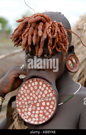 Ritratto di donna i Mursi persone che indossano un grande colorato piastra a labbro e strana pettinatura Etiopia Foto Stock