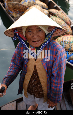 Una donna in un cappello conico lavora sul pesce quay vicino al mercato di Hoi An in Vietnam. Foto Stock
