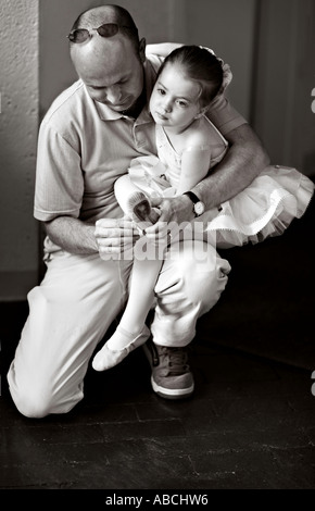 Moderno e giovane padre aiuta la sua bellissima figlia di cinque anni ha messo in scarpe da ballo per il suo recital Foto Stock