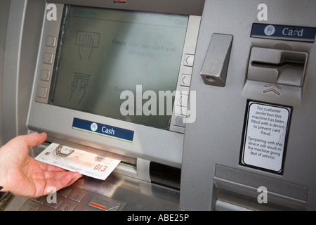 Bancomat cashpoint macchina per contanti buco nella banca del muro teller rimuovere schermata con una mano del pensionato prendendo £10 banconote in sterline. Inghilterra Gran Bretagna Foto Stock