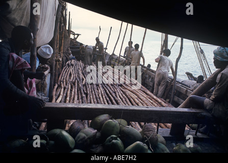 Con un uomo a sinistra tenere il punteggio--un nodo per ogni 20 poli--un dhow si riempie lentamente con un carico segregati in casa dei poli di mangrovie Foto Stock