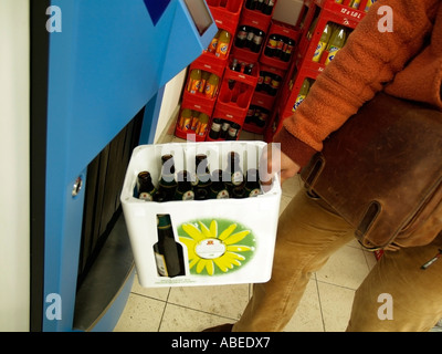 Signor persona portando cassa di birra con Deposito restituibile bottiglie in retromarcia della macchina distributrice ad un punto per si svuota nel supermercato Foto Stock