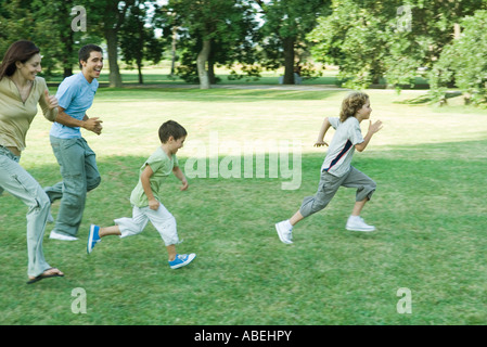 Famiglia all'aperto in esecuzione su prato erboso in una giornata di sole Foto Stock