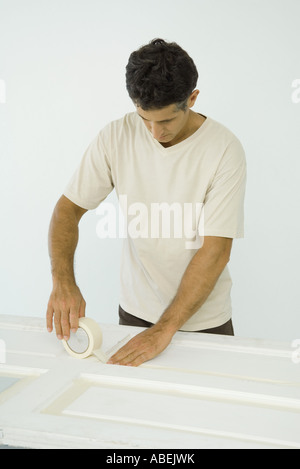 Uomo di mettere del nastro adesivo sulla porta Foto Stock