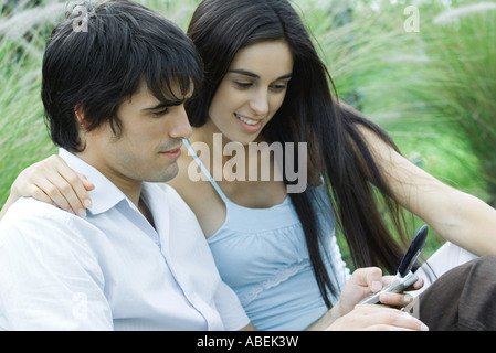 Coppia giovane all'aperto insieme, guardando il telefono cellulare Foto Stock
