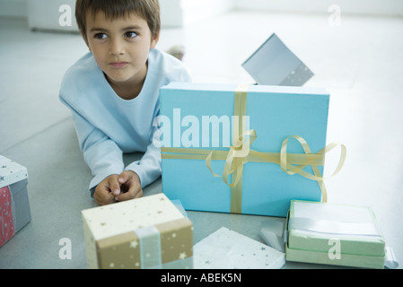 Ragazzo disteso sul pavimento accanto ai regali di Natale Foto Stock