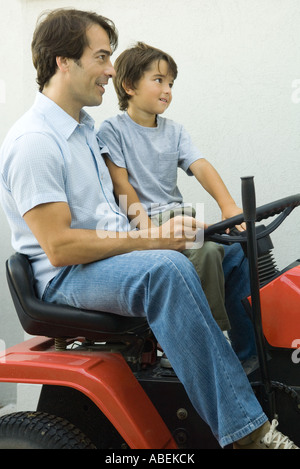 Padre e figlio sui tosaerba di equitazione Foto Stock