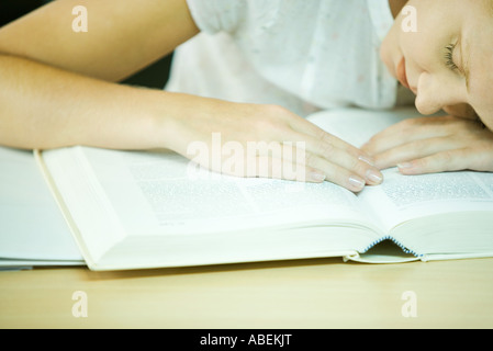 Collegio femminile studente seduto con la testa sul libro, close-up Foto Stock