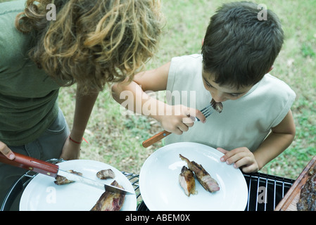 Due ragazzi di mangiare carne alla griglia Foto Stock