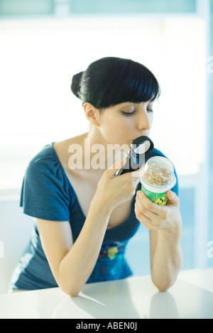 Donna che guarda lo yogurt attraverso la lente di ingrandimento Foto Stock