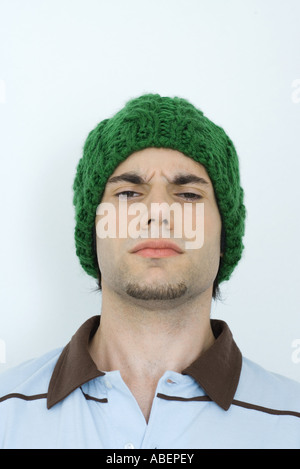 Giovane uomo che indossa knit hat, solcando brow, ritratto, close-up Foto Stock