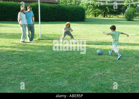 Ragazzi che giocano a calcio mentre i genitori guardare Foto Stock