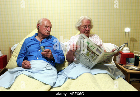 Coppia senior in letto, donna quotidiano di lettura Foto Stock