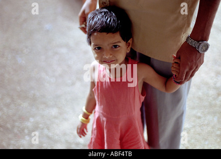 Un bambino di cinque anni, Indian ragazza sorridente con fiducia mentre tiene il suo padre s mano Foto Stock