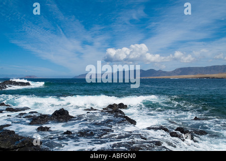 Dh Caleta de CABALLO LANZAROTE Surf di onde che si infrangono sulle rocce laviche El Risco de Famara scogliere sul mare e sulla baia Foto Stock