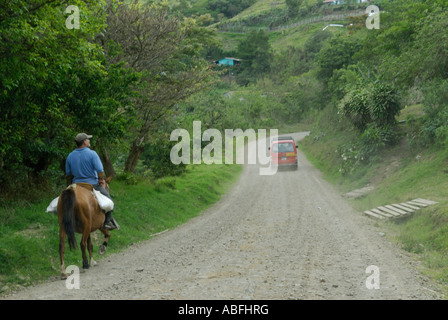 Un turismo mini bus passa un uomo su un cavallo vicino al Lago di Arenal Costa Rica Foto Stock