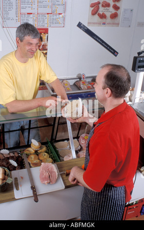 L'uomo nel negozio di macellaio acquisto di carne aventi cordiale chiacchierata con contatore shop assistant Foto Stock