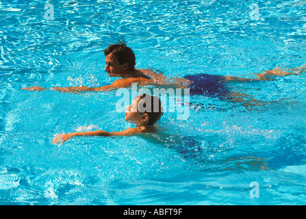 Un padre dà una lezione di nuoto al suo bambino di nove anni Foto Stock
