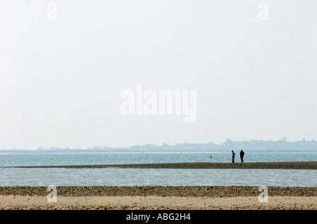 La gente camminare lungo la barra di sabbia sulla Mersea island Essex REGNO UNITO Foto Stock