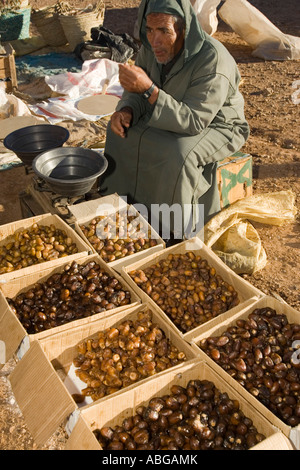 Berber uomo in djellaba vendita di scatole di datteri freschi settimanale mercato outdoor boulmane du Dades Marocco Foto Stock