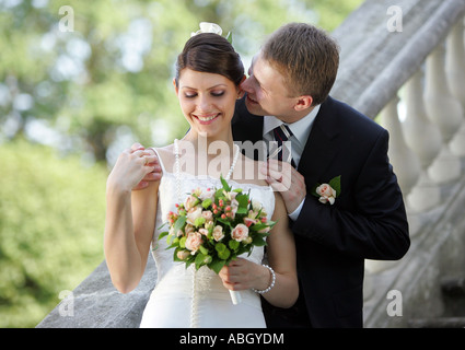 Una sposa in un bianco tradizionale abito da sposa visto qui sorridente come suo marito abbraccia. Foto Stock