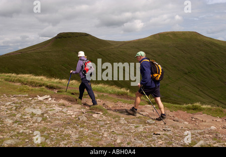 Coppia matura camminando sul sentiero in Brecon Beacons, mais Du e Pen y Fan in background Powys South Wales UK Foto Stock