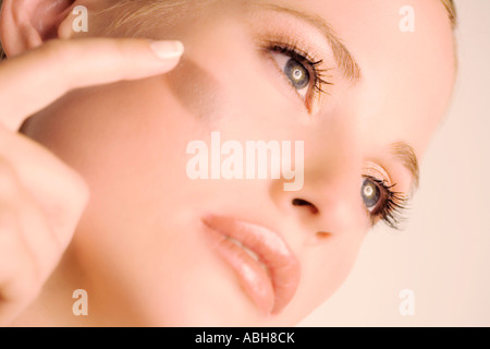 Ritratto di una giovane donna che formano la sua guancia con un pennello, interni (studio) Foto Stock