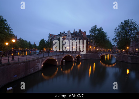 Vista su ponte illuminato di case a capanna in serata Keizersgracht e Leidsegracht Amsterdam Olanda Paesi Bassi Foto Stock