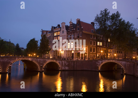 Vista su ponte illuminato di case a capanna in serata Keizersgracht e Leidsegracht Amsterdam Olanda Paesi Bassi Foto Stock