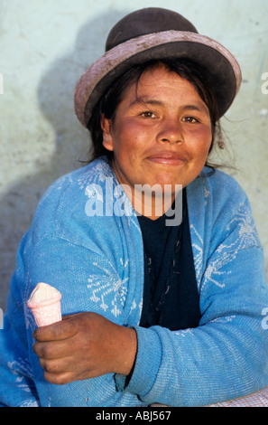 Uros, vicino a Puno, Perù. Donna che indossa cappello tradizionale di mangiare un cono di meringa dolce. Foto Stock