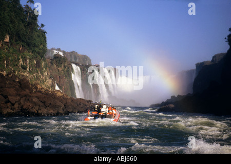 Iguassu Falls, Stato di Parana, Brasile. I turisti in barca ai piedi delle cascate; rainbow. Foto Stock