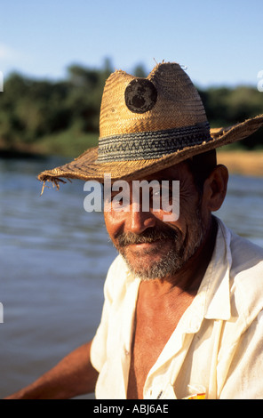 Pantanal, Mato Grosso Membro, Brasile; il ritratto di un uomo sorridente indossando un travagliato cappello di paglia con il fiume dietro. Foto Stock