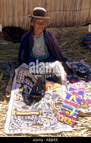 Il lago Titicaca, Perù. Vecchia donna mostra souvenir panno ricamato in un villaggio sull'isola galleggiante di Uros. Foto Stock