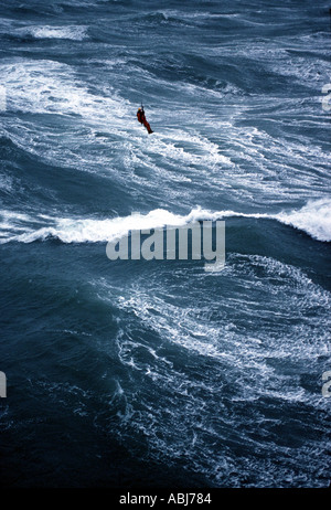 Verricello in elicottero sopra l uomo di mare mosso e onde Foto Stock