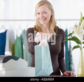 Negozio di abbigliamento addetto alla vendita consegna pacchetto su contatore Foto Stock