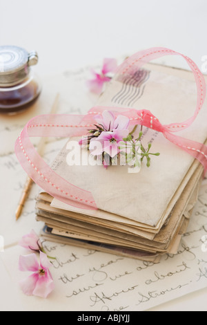 Pila di vecchi lettere accanto ai fiori e bottiglia di inchiostro Foto Stock