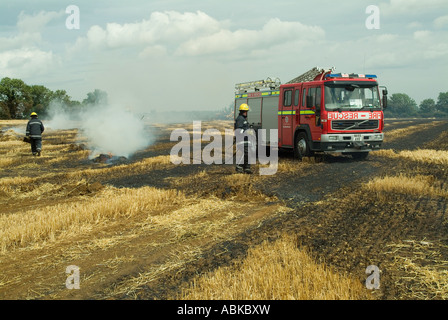 I vigili del fuoco di masterizzazione estinguente orzo campo dopo l'imballatrice fire, nello Yorkshire, Regno Unito Foto Stock