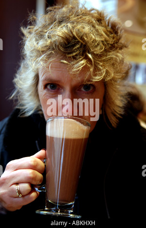La bionda signora beve una tazza di cioccolato caldo al caffè Costa cafe in Brighton Foto Stock