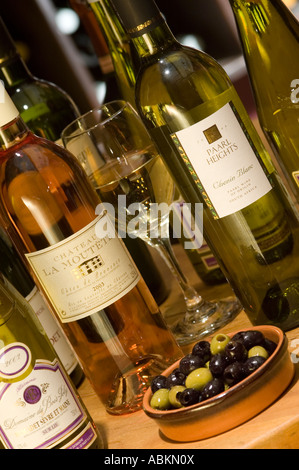 Una selezione di bottiglie di vino su una tavola di acqua potabile con una ciotola di olive Foto Stock