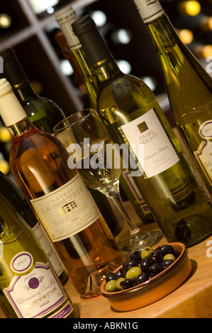 Una selezione di bottiglie di vino su una tavola di acqua potabile con una ciotola di olive Foto Stock