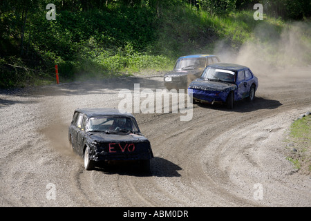 Folkrace banger racing cars curva attraverso la campagna le vie alzando nuvole di polvere a Torslanda Racecourse a Göteborg in Svezia Foto Stock