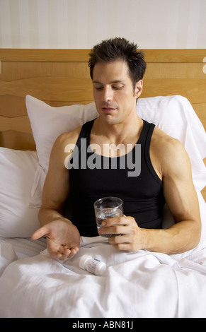 Uomo nel letto, tenendo in pillole Foto Stock