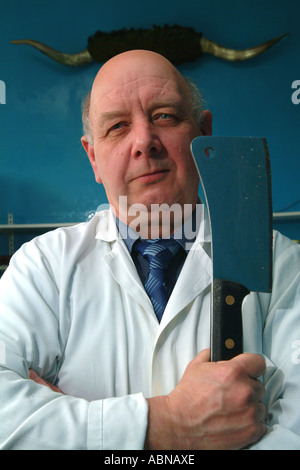 Butcher si erge nel suo negozio con una carne intelligente nel suo lato di fronte una serie di corna REGNO UNITO Foto Stock