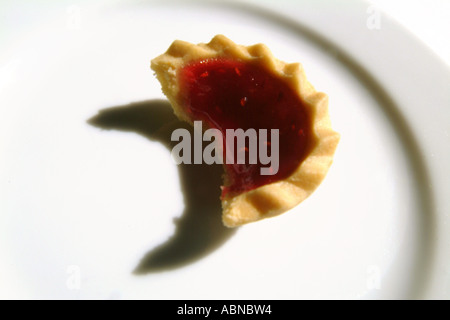 Jam tart su una piastra bianca con un morso presa UK Foto Stock