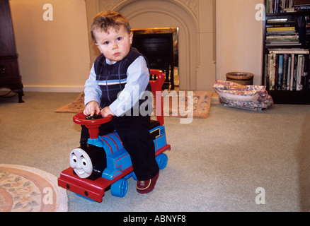 STUDIO Dicembre giovane ragazzo seduto sul suo nuovo regalo di Natale di Thomas Il serbatoio del motore del giocattolo Foto Stock