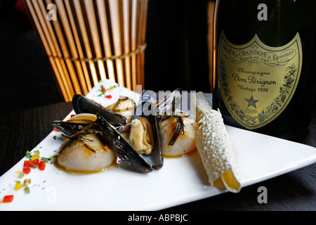 Cozze su una piastra bianca e una bottiglia di Don Perignon champagne Foto Stock