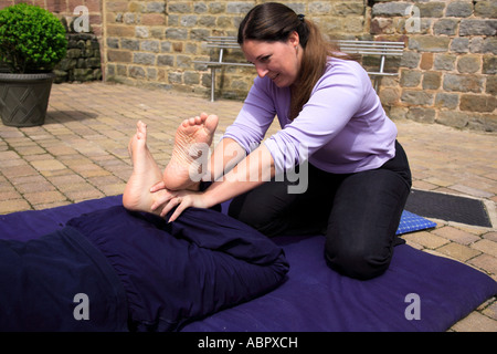 Lo stretching dei quadricipiti come parte di un Thai massaggio corpo Foto Stock