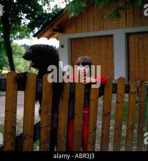 Ragazza e un nero francese Briard cane dietro il cancello di legno. Foto di Willy Matheisl Foto Stock