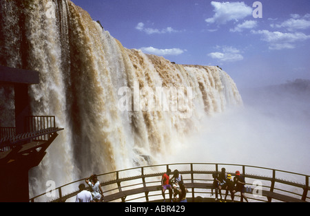 Iguassu Falls, Brasile. Enorme cascata con gente seduta in un semi-circolare di area di visualizzazione in primo piano. Foto Stock